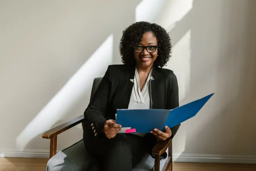 Woman with glasses holding an open folder of papers
